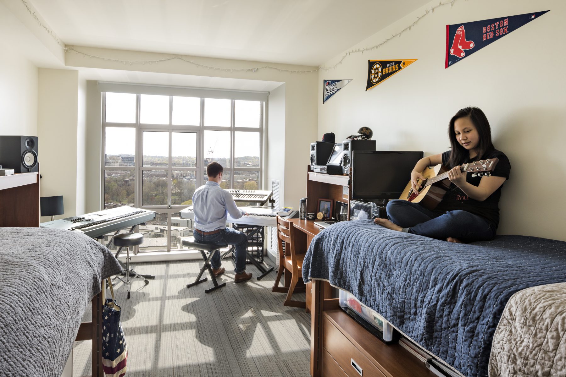 Berklee College Dorm Room, one student plays piano while the other plays guitar on their bed.