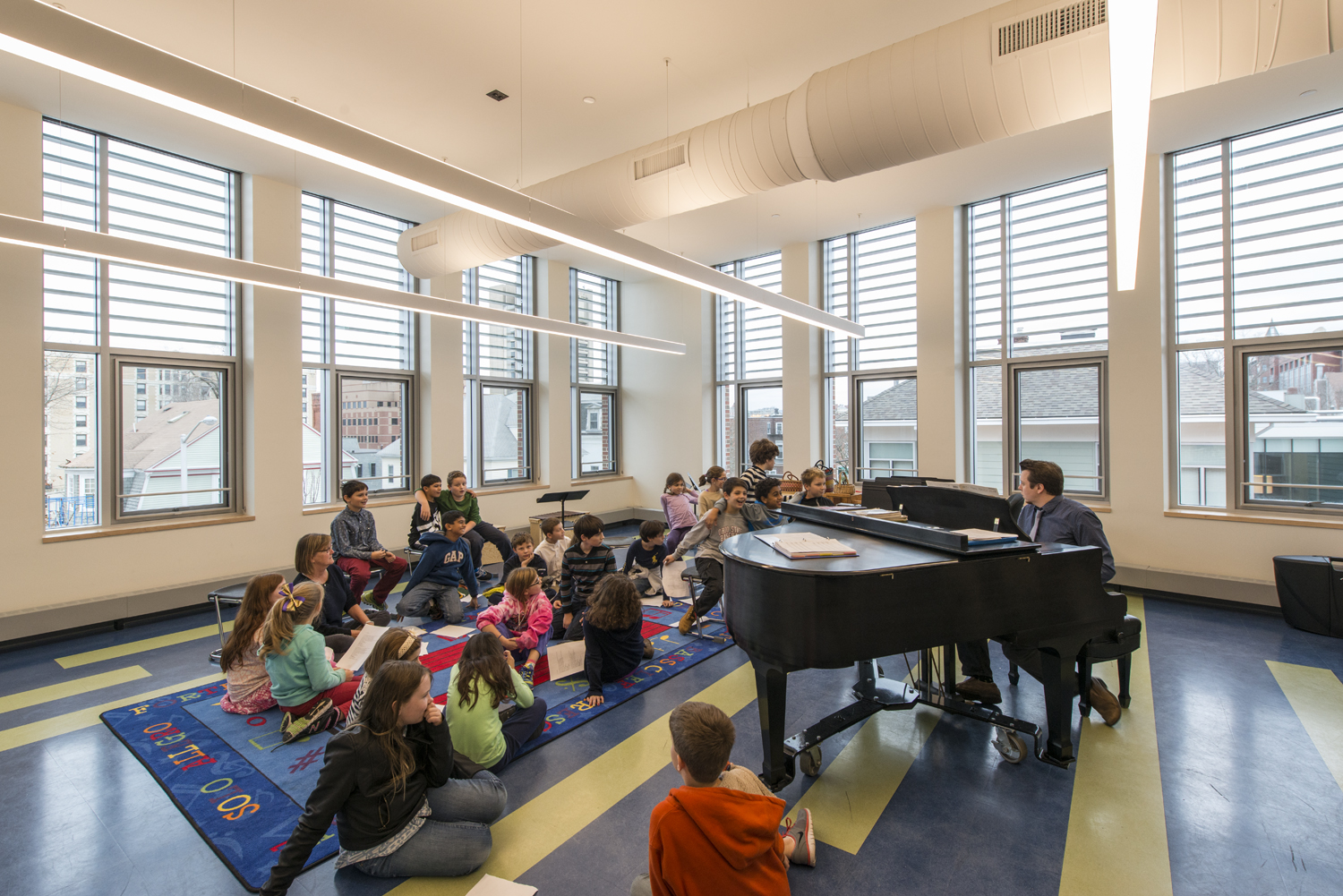 Wheeler School Music Room, a teacher plays piano to a group of young students
