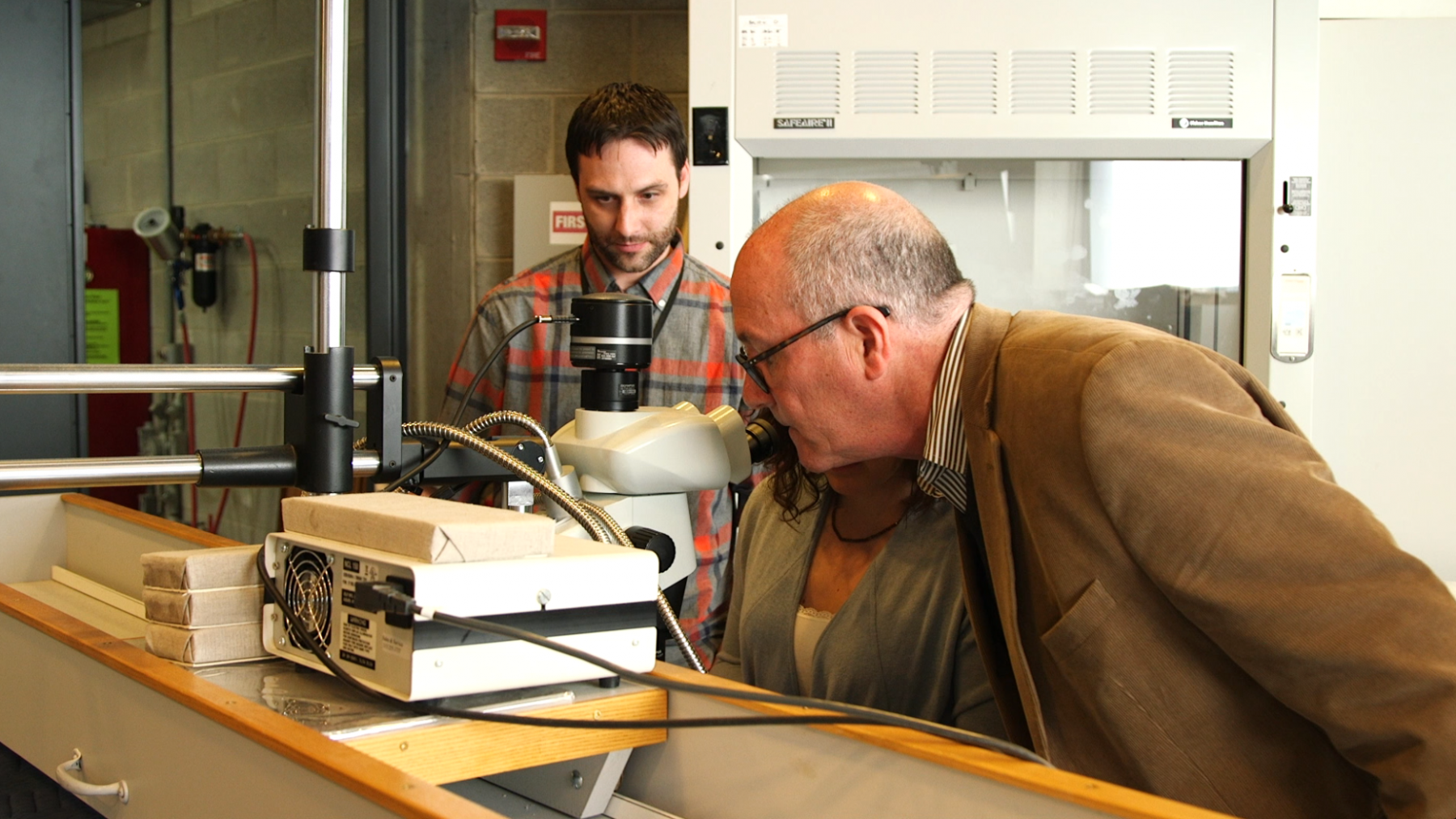 Conservators as the yale Center looking through a microscope.