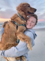 Tyler Tracy holding his dog on the beach