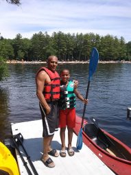 Jonathan White on a dock with his son holding a kayak paddle