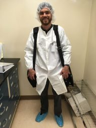 Andy with booties, a lab coat, and hairnet on