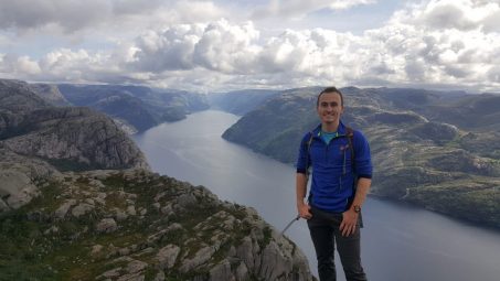 Alex O Climbing with river and cliffs in background