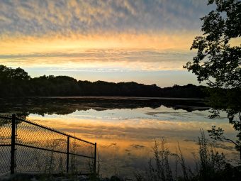 a photo of the sunset reflecting off of the surface of a lake