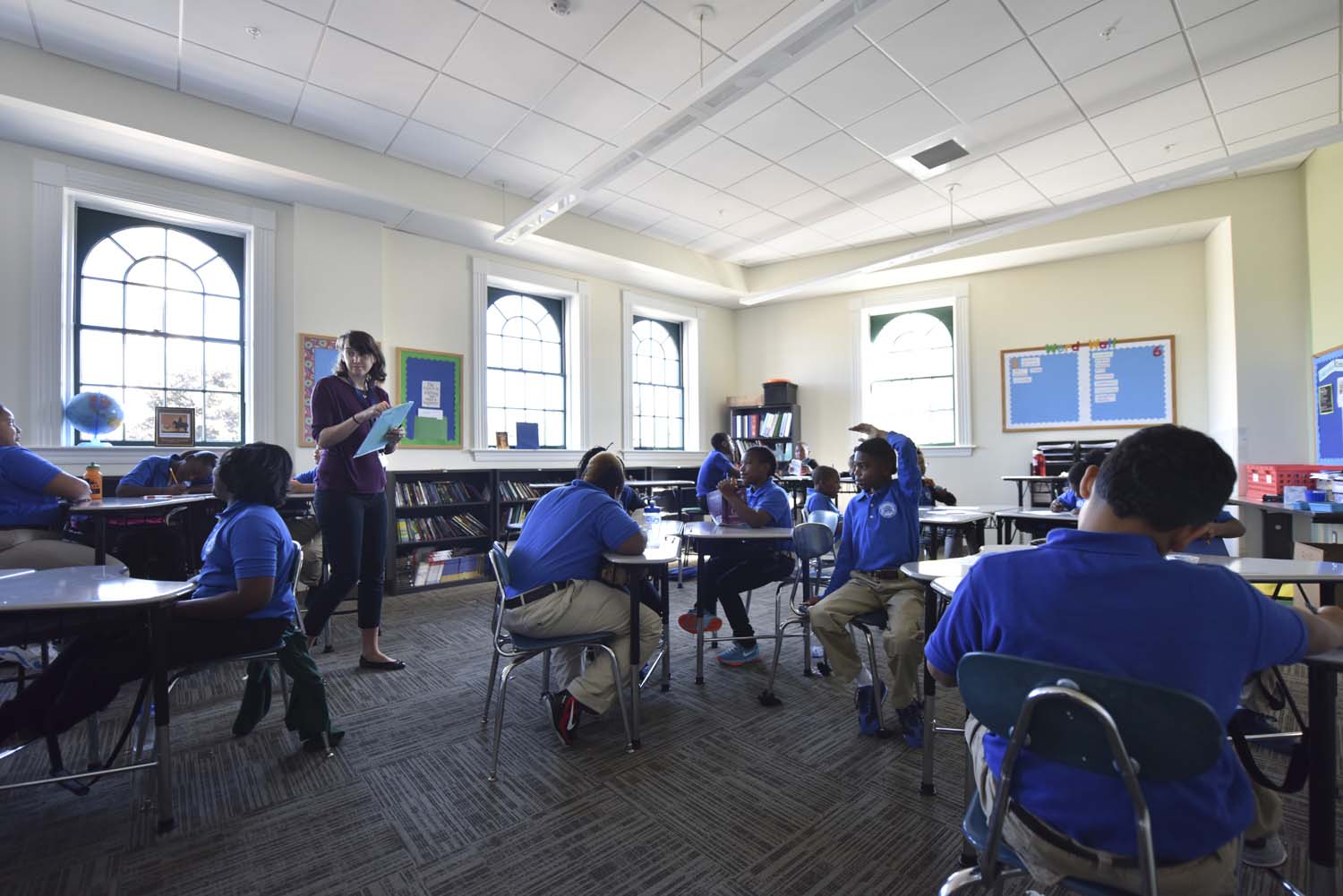 Codman Academy Classroom, a teacher walks around the class with a clipboard