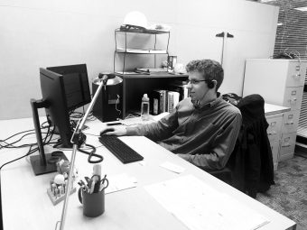 A photo of Colin working at his desk with headphones on
