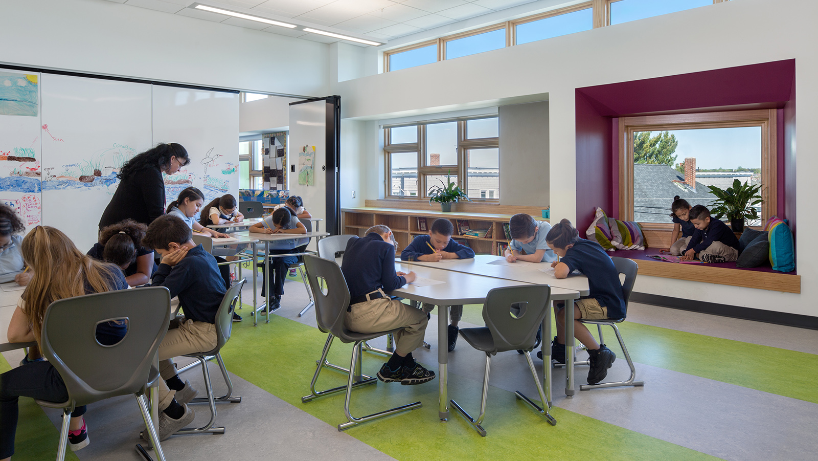 Irwin Jacobs Elementary School Interior, classroom with 4 large desks and whiteboard walls