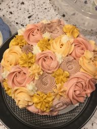 A photo of a cake with rose petal icing designs