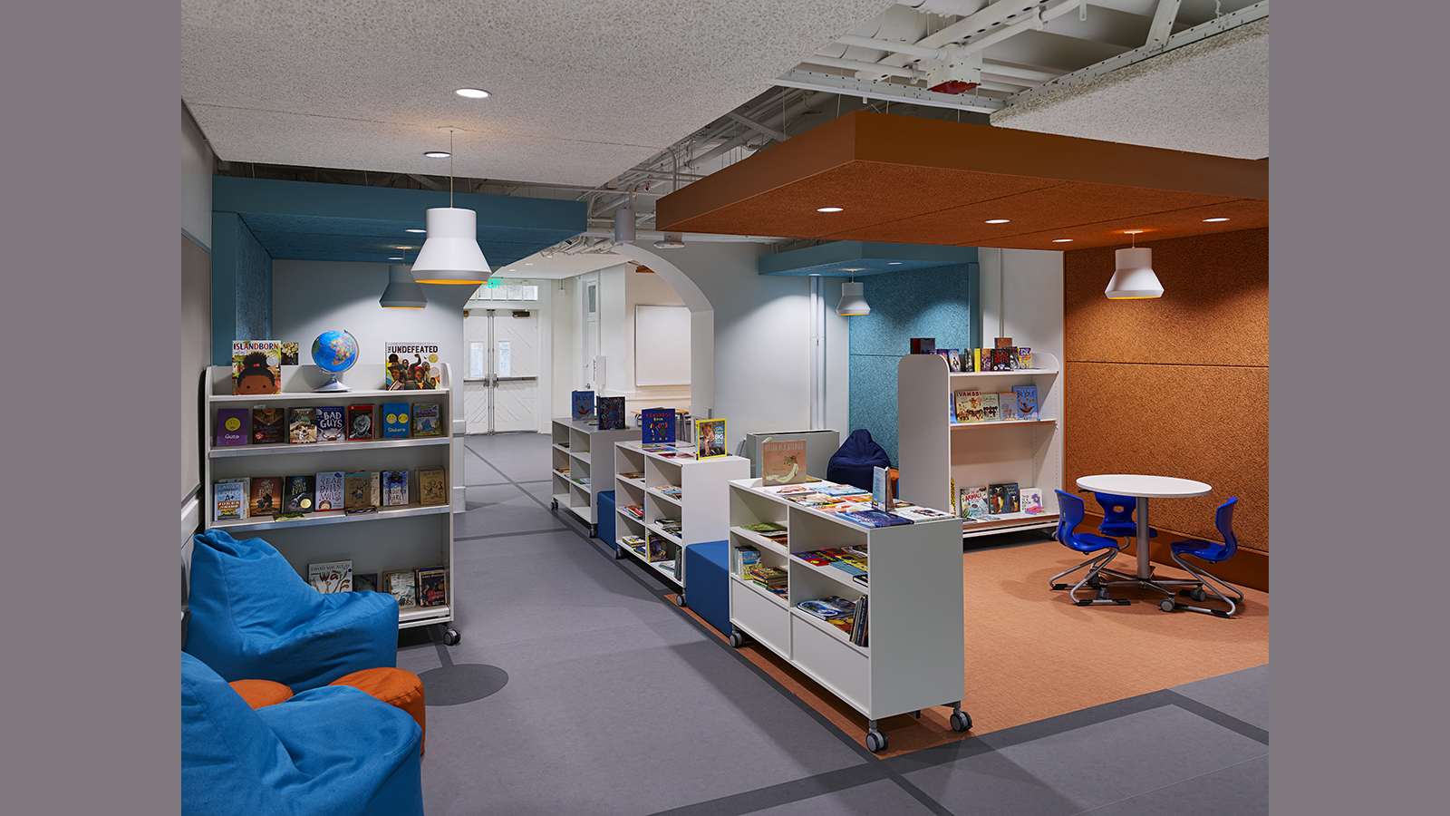 Creative Minds International Public Charter School, seating area with bookshelves and colorful orange, and blue walls