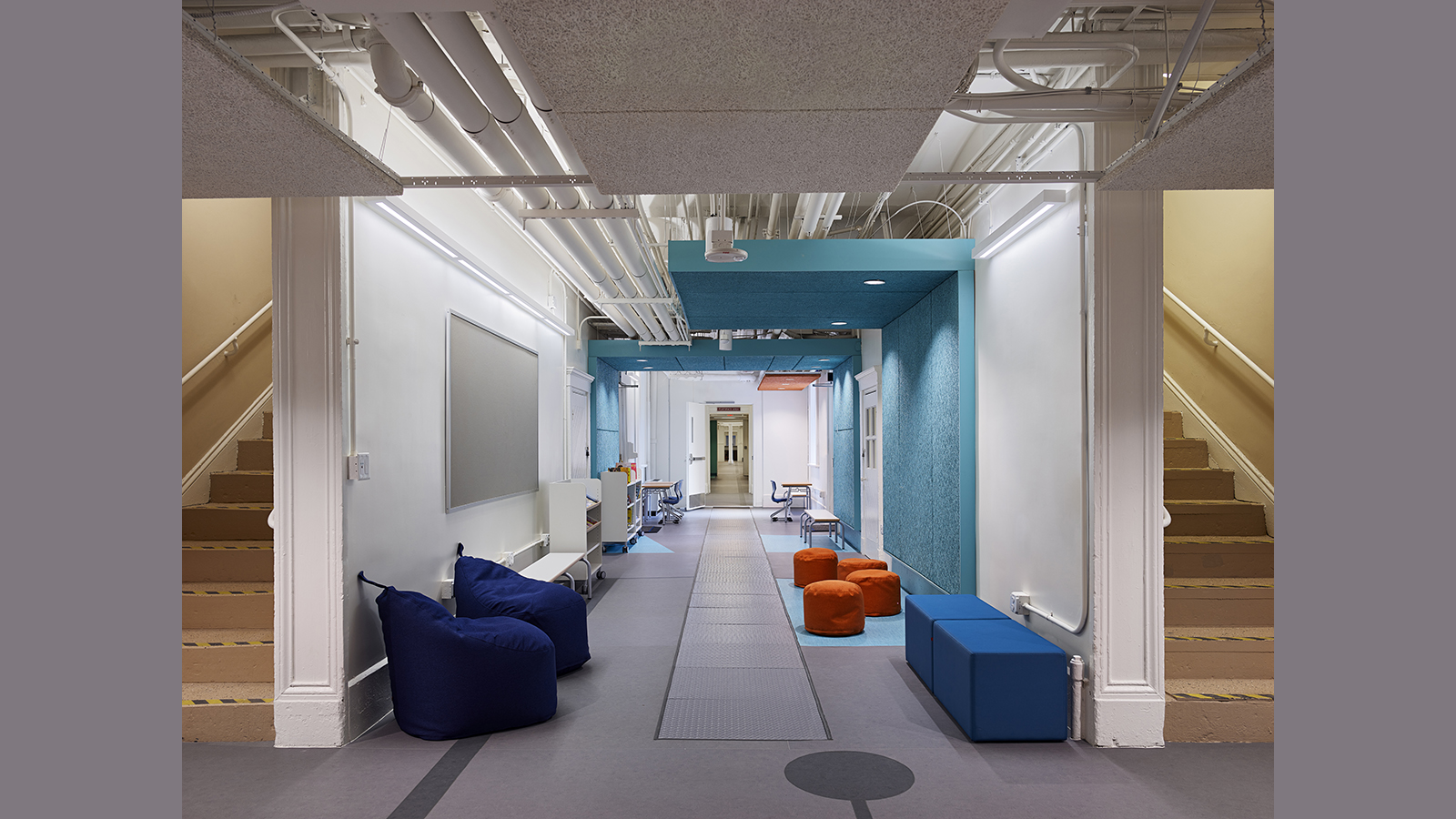 Creative Minds International Interior, a hallway with seating, tow stairwells on either side